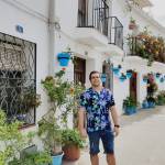 miguel in summer clothes standing in front of a beautiful building