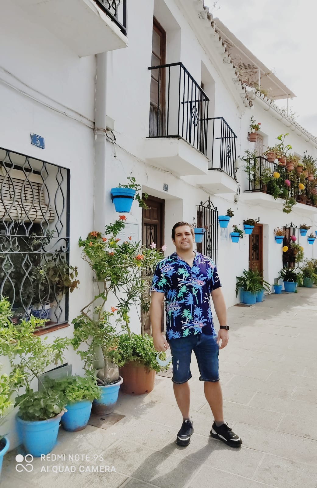 miguel in summer clothes standing in front of a beautiful building