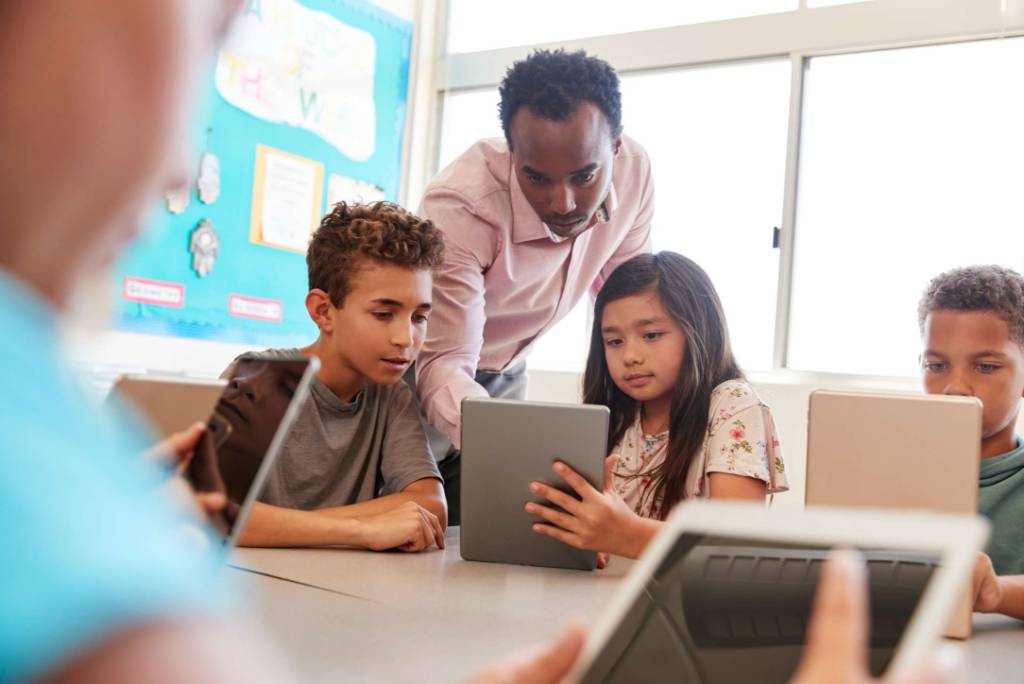 A teacher assisting a number of young students in the classroom