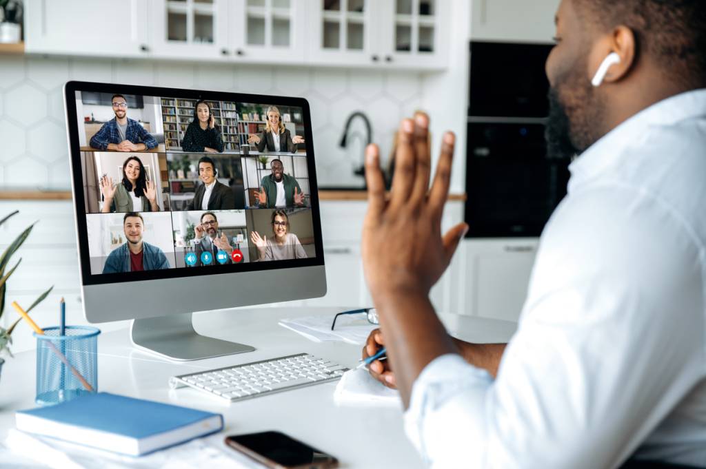 Video call, virtual meeting. Over shoulder view of african american man at computer screen with multinational group of successful business people, virtual business meeting, work from home concept