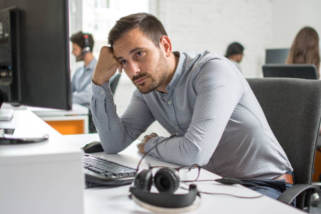 Worried bearded man looking at computer screen in office.