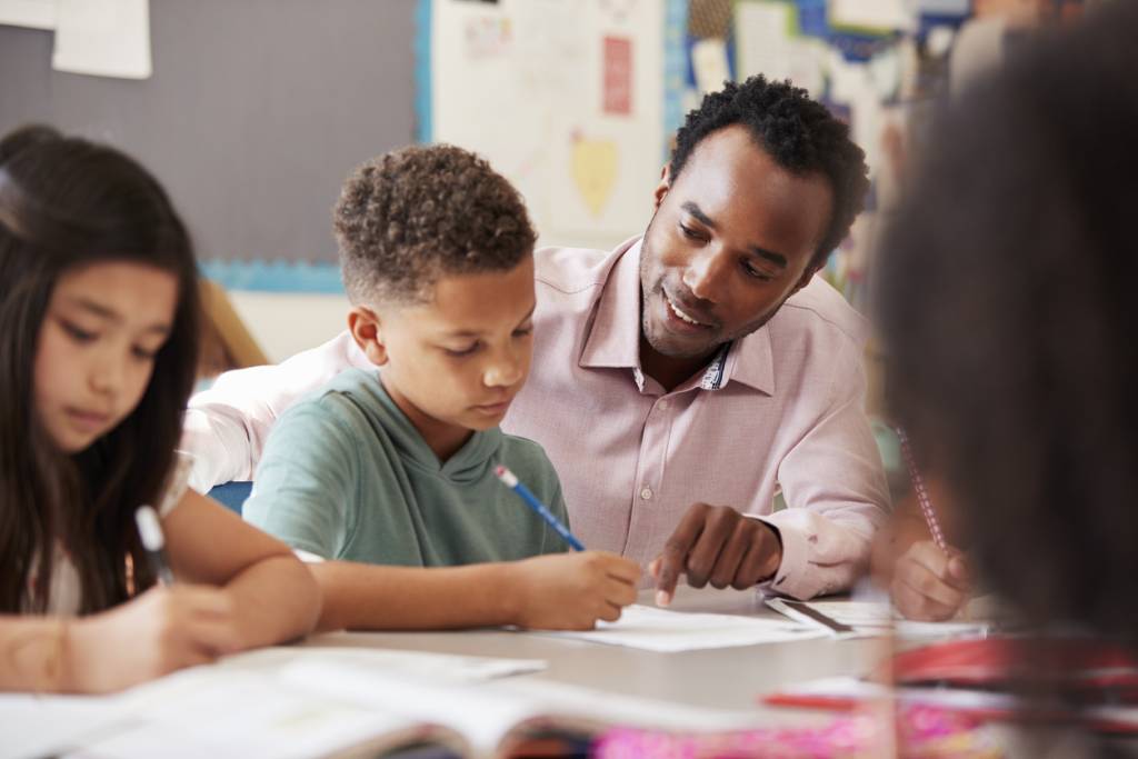 male teacher helping his student with his class work