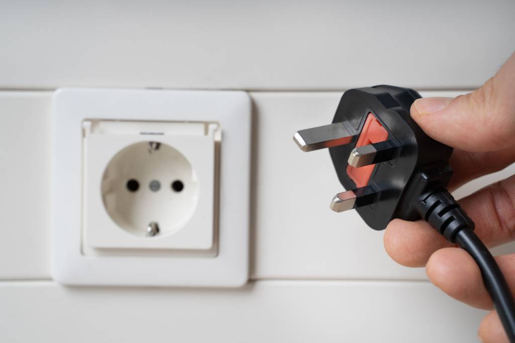 Hand Holding Incompatible AC Plug Near Wall Socket. Video conferencing interoperability