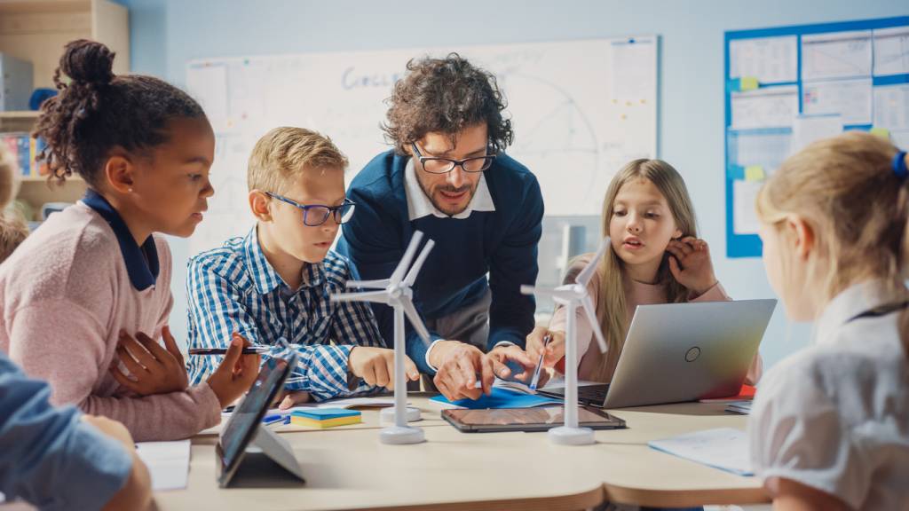 Teacher helping his students with a task using technology