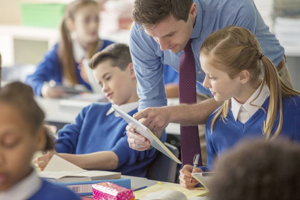 Teacher with his pupils in classroom using tablet pc