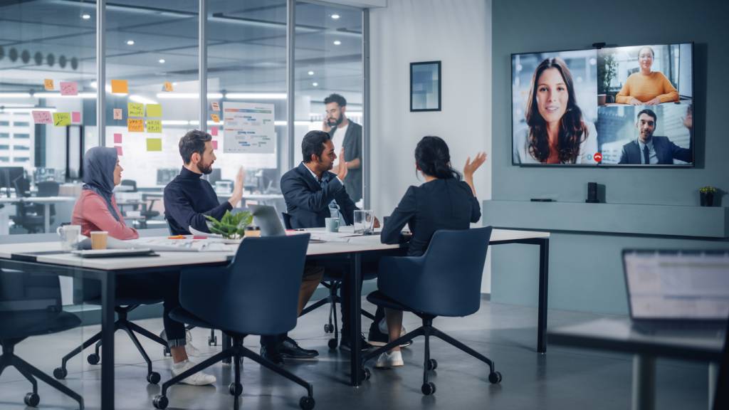 Businesspeople do Video Conference Call with a large screen in Office Meeting Room. Diverse Team of Creative Entrepreneurs at Big Table have Discussion. Specialists work in Digital e-Commerce Startup