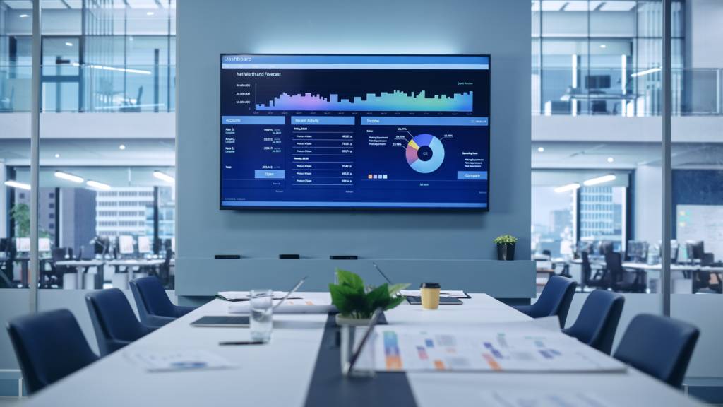 Modern Empty Meeting Room with Big Conference Table with Various Documents and Laptops on it, on the Wall Big TV with Big Data, Statistics, Talks about Company Growth. Contemporary Designed Workplace.