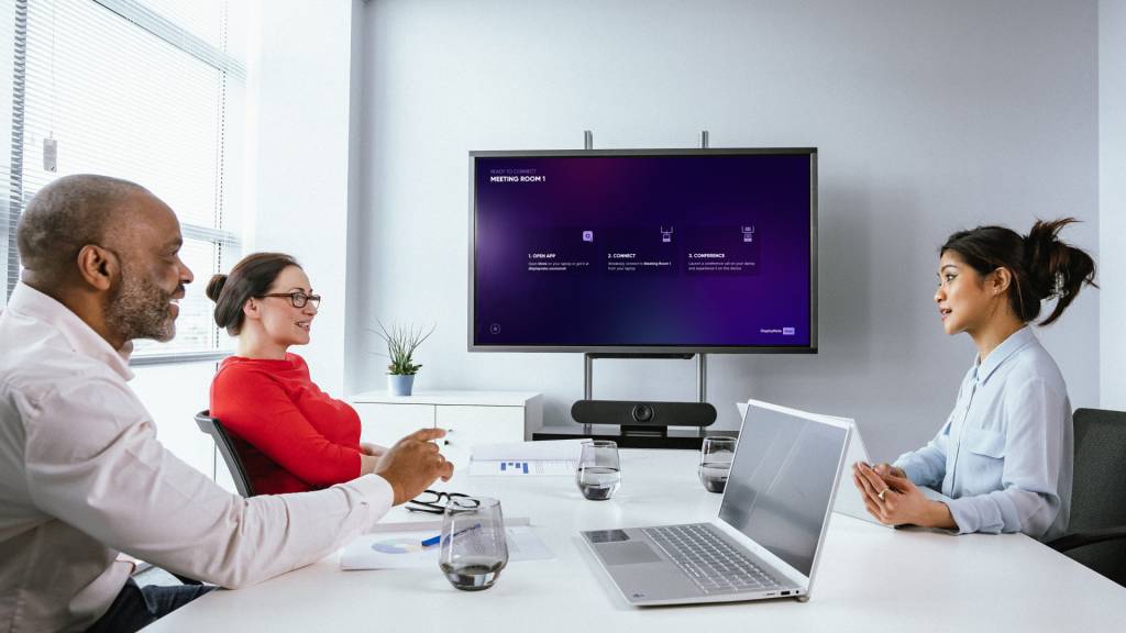 Three colleagues having a discussion during a meeting, using BYOM solution, Omni.